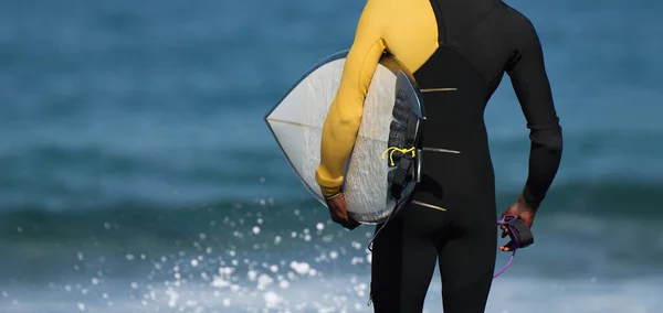 海に出る準備ができているサーファー 黒いウェットスーツのサーファーは水に入る準備ができています — ストック写真