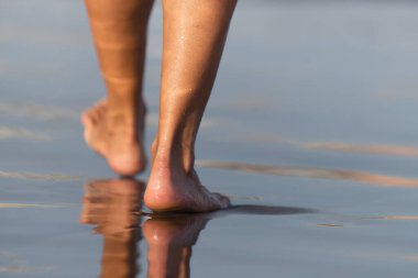 Okyanus su dalgalarında yürüyen yalınayak kadın