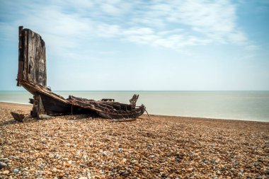 Remains of an old wooden fishing boat on stony beach in Hastings clipart