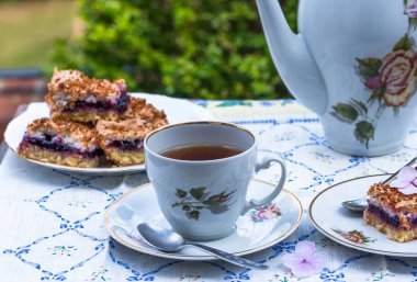 Bahçede bir tabloda çay ve blackcurrant kek yola çıktı