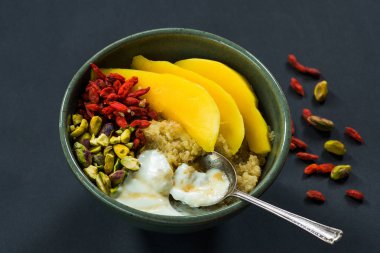 Mango, Antep fıstığı, goji meyveleri ve bal yoğurt ile Quinoa yulaf lapası