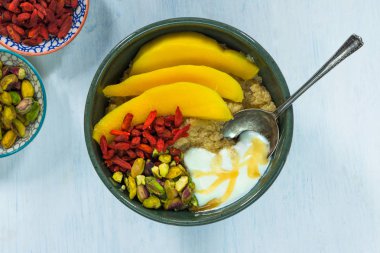 Mango, Antep fıstığı, goji meyveleri ve bal yoğurt ile Quinoa yulaf lapası