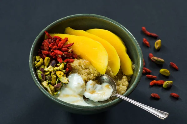 Quinoa porridge with mango, pistachio nuts, goji berries and honey yogurt — Stock Photo, Image