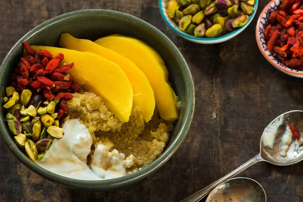 Quinoa porridge with mango, pistachio nuts, goji berries and honey yogurt — Stock Photo, Image