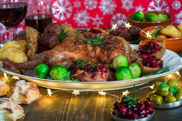 Festlicher Entenbraten auf Holztisch mit Rosenkohl, Bratkartoffeln, Äpfeln und Preiselbeersoße — Stockfoto