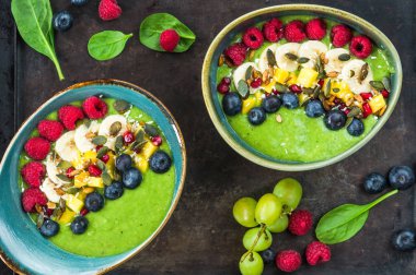 Yeşil avokado, ıspanak ve üzüm güler yüzlü taze meyve ile süslenmiş.