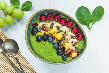 Yeşil avokado, ıspanak ve üzüm güler yüzlü taze meyve ile süslenmiş.