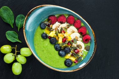 Yeşil avokado, ıspanak ve üzüm güler yüzlü taze meyve ile süslenmiş.