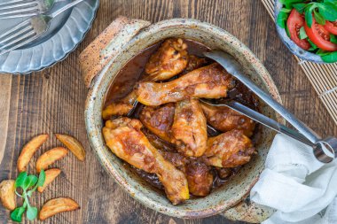 Zencefilli bira soslu tavuk budu patates dilimleri ve ahşap masa üzerinde salata.