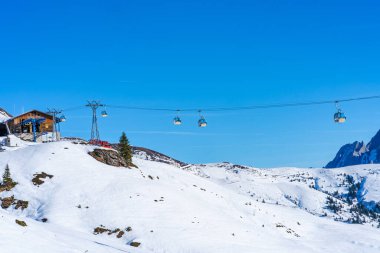 GRINDELWALD-FIRST, SWITZERLAND - JANUARY 15 2020: Skiers in ski gondolas go to the top of The First mountain in a popular Jungfrau Region ski resort which offers plenty of snowy activities