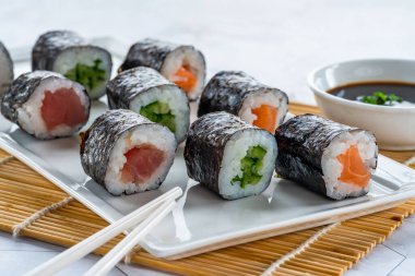 Somon, ton balığı, salatalık ve soya sosu daldırma ile bir seçim suşi rulo.