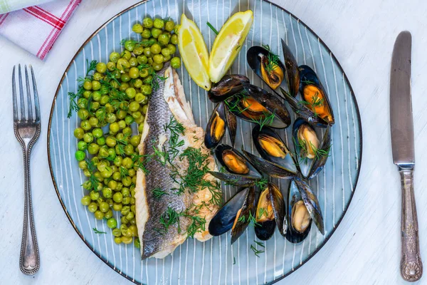 Sea bass with peas, mussels and lemon garnished with fresh dill - overhead view