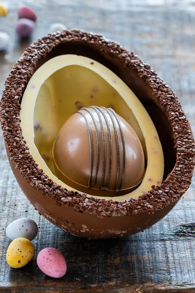 Easter chocolate egg inside chocolate shell on wooden table