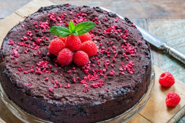 Çikolata ve ahududu turtası. Taze meyve ve nane ile süslenmiş.