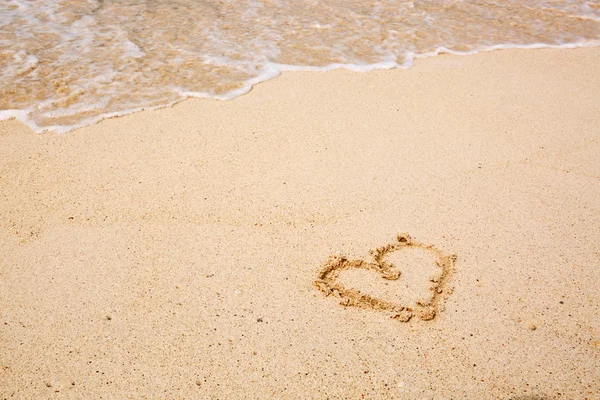 Heart symbol on the sand and sea wave. — Stock Photo, Image