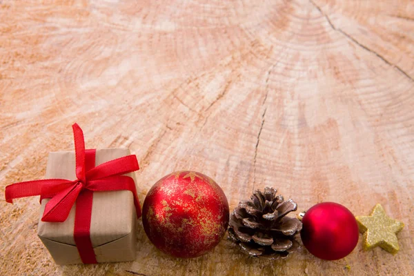 Weihnachtsgeschenk mit Christbaumkugel und Tannenzweigen auf Holzgrund. — Stockfoto