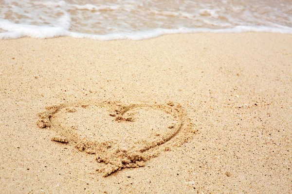 Heart symbol on the sand and sea wave. — Stock Photo, Image