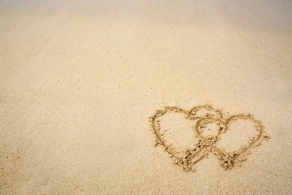 Två hjärtan dras på sanden på en strand. — Stockfoto