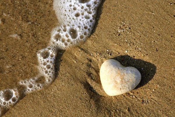 Coeur de pierre sur la plage dans les vagues . — Photo