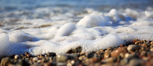 Ondas de lavado sobre la playa de grava, macro disparo. — Foto de Stock