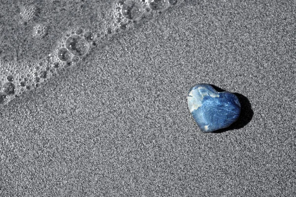 Pierre grise en forme de cœur repose sur le sable . — Photo