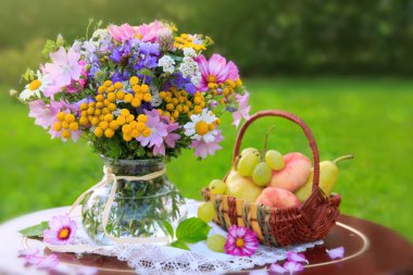 Renkli yabani çiçekler ve meyve sepeti.