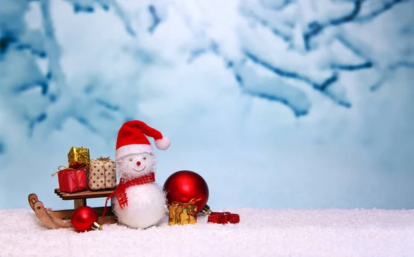 Schneemann mit Weihnachtsgeschenken auf dem Schlitten isoliert auf blauem Winterhintergrund. — Stockfoto