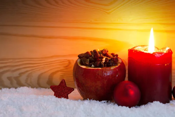 Рождественская свеча и жареное яблоко с изюмом . — стоковое фото