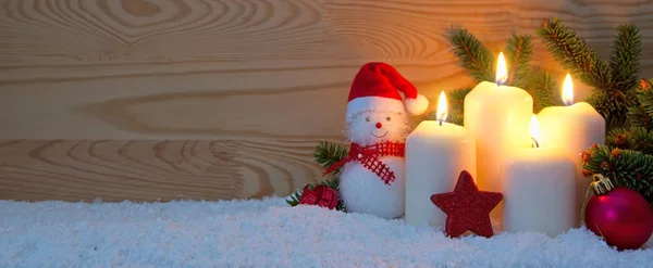 Τέσσερα λευκά κεριά κάψιμο και χιονάνθρωπος . — Φωτογραφία Αρχείου