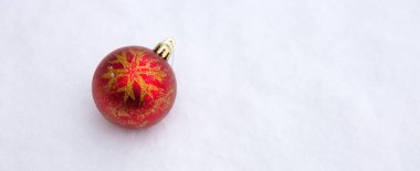 Beyaz kar üzerinde kırmızı Noel topu.