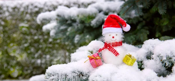 Snögubbe med julklappar isolerad på granen med vit snö. — Stockfoto