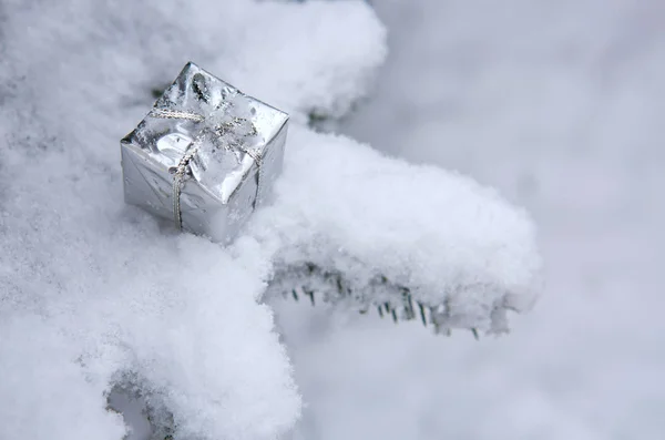 Silbernes Weihnachtsgeschenk auf weißem Schnee. — Stockfoto