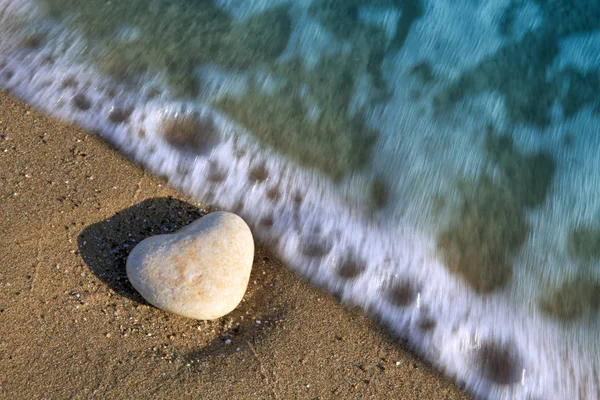 Steen hart op het strand in de golven. — Stockfoto