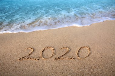 Yeni Yıl 2020 konsepti geliyor. 2020 yazıtları ıslak kumsalda, deniz suyu dalgalarıyla yazılmış.