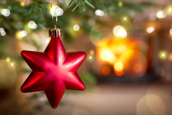 Estrella roja de Navidad contra una chimenea de piedra. Bokeh fondo de luz de vacaciones. —  Fotos de Stock