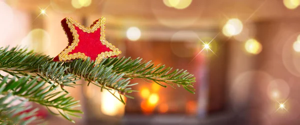 Estrella roja de Navidad contra una chimenea de piedra. Bokeh fondo de luz de vacaciones. —  Fotos de Stock
