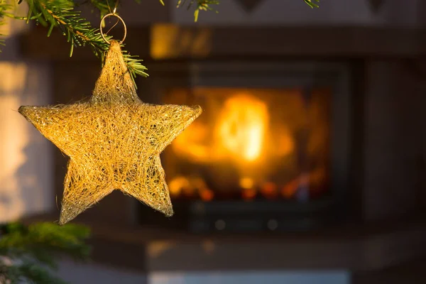 Golden Christmas star against a stone fireplace. Bokeh holiday light background.
