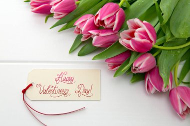 Vlentines Günü kartı ve ahşap arka planda bir buket güzel lale..