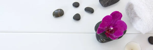 Spa o bienestar con orquídeas rosadas, velas y piedras negras. — Foto de Stock