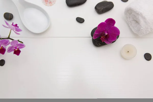Ajuste de spa con orquídeas rosadas, piedras negras sobre fondo de madera blanca . — Foto de Stock