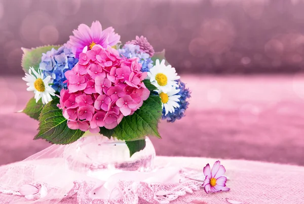 Ramo de flores de colores en jarrón de vidrio aislado en rosa . — Foto de Stock