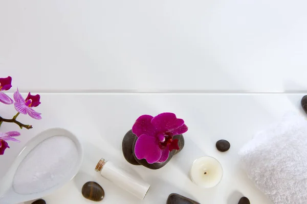 Ajuste de spa con orquídeas rosadas, piedras negras y sales de baño sobre fondo de madera blanca . — Foto de Stock