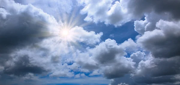Blauwe lucht met grijze wolken en zonlicht.. Natuur achtergrond. — Stockfoto