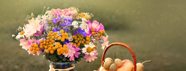Bukett färgglada vilda blommor och frukt korg. — Stockfoto