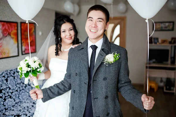 快乐与气球在他手中，新郎在室内在婚礼当天，新娘在后台. — 图库照片