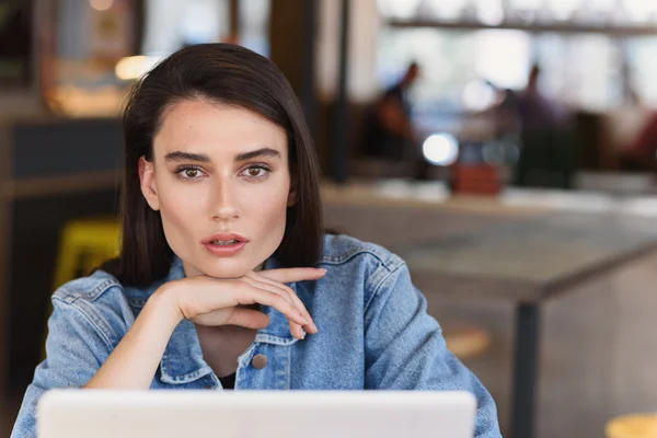 Modernes Mädchen, das arbeitet und in eine Kamera schaut — Stockfoto