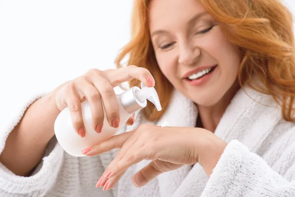 Vrolijke dame knijpende moisturizer bij de hand — Stockfoto