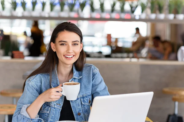Fröhliche Studentin in einem Café, die in die Kamera lächelt — Stockfoto