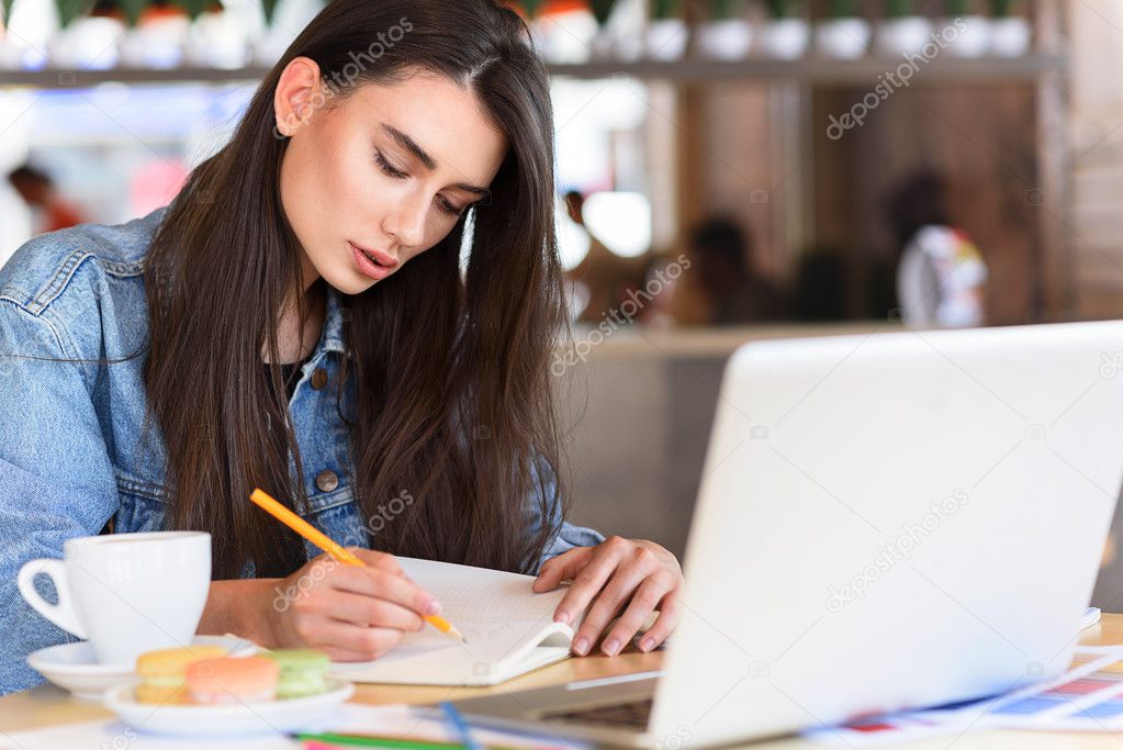 female freelancer writing in her paper notebook