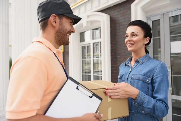 Courier making delivery to beautiful woman — Stock Photo, Image